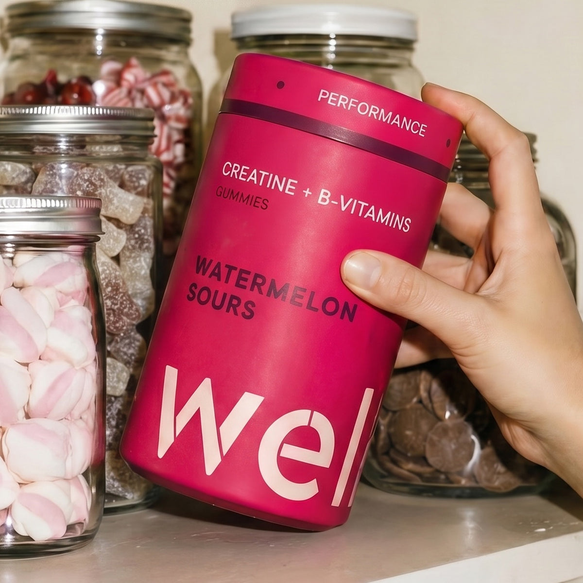 WELLF creatine gummies on a retro sweet-shop shelf, watermelon sours in a striped paper bag